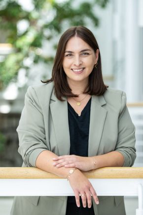 EVM-2025-070_angepasst Eine Frau mit roten Haaren ist professionell gekleidet und lächelt freundlich.