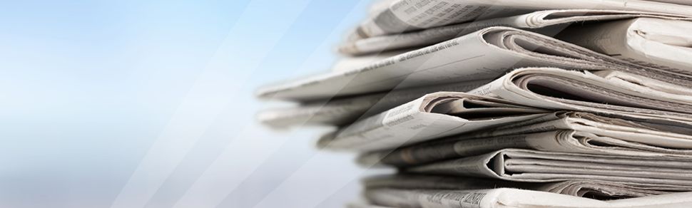 Ein Stapel von Zeitungen vor blauem Hintergrund.