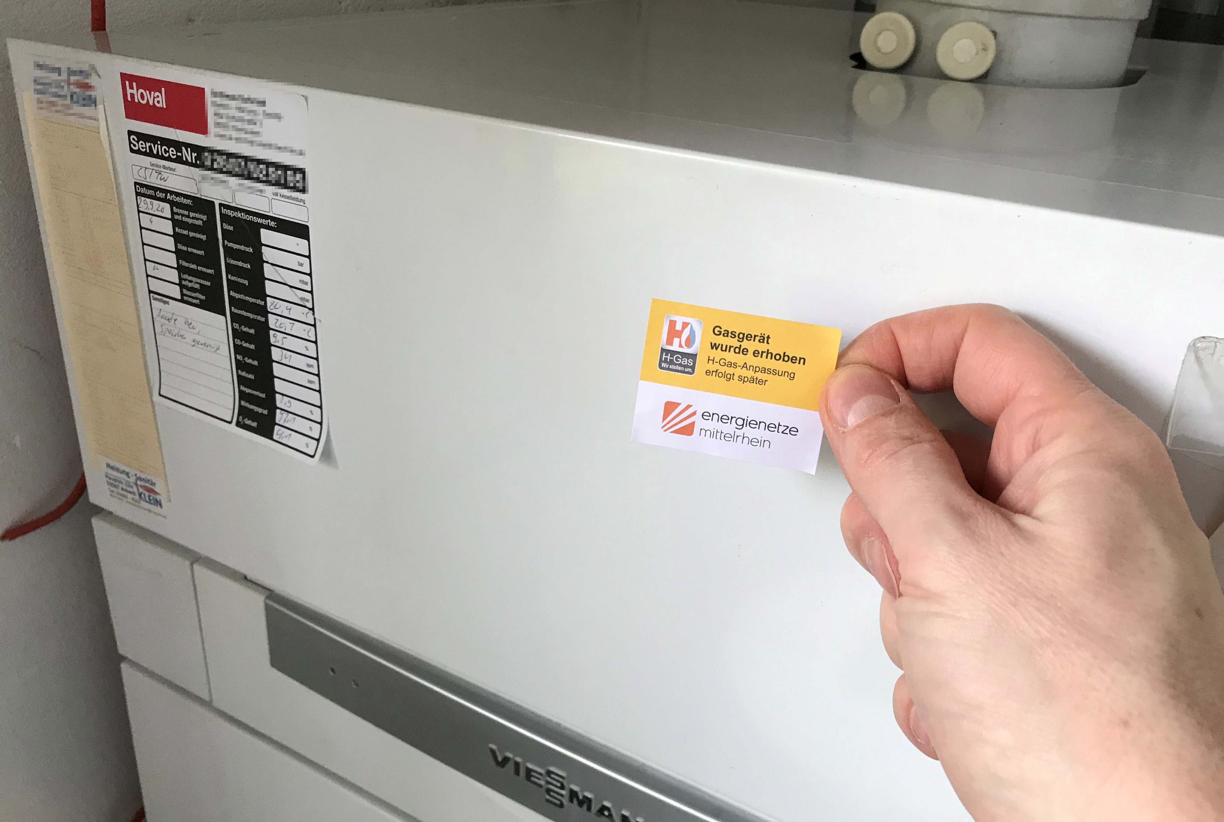 Eine Hand hält einen Zettel mit der Aufschrift "Gasgerät wurde erhoben".