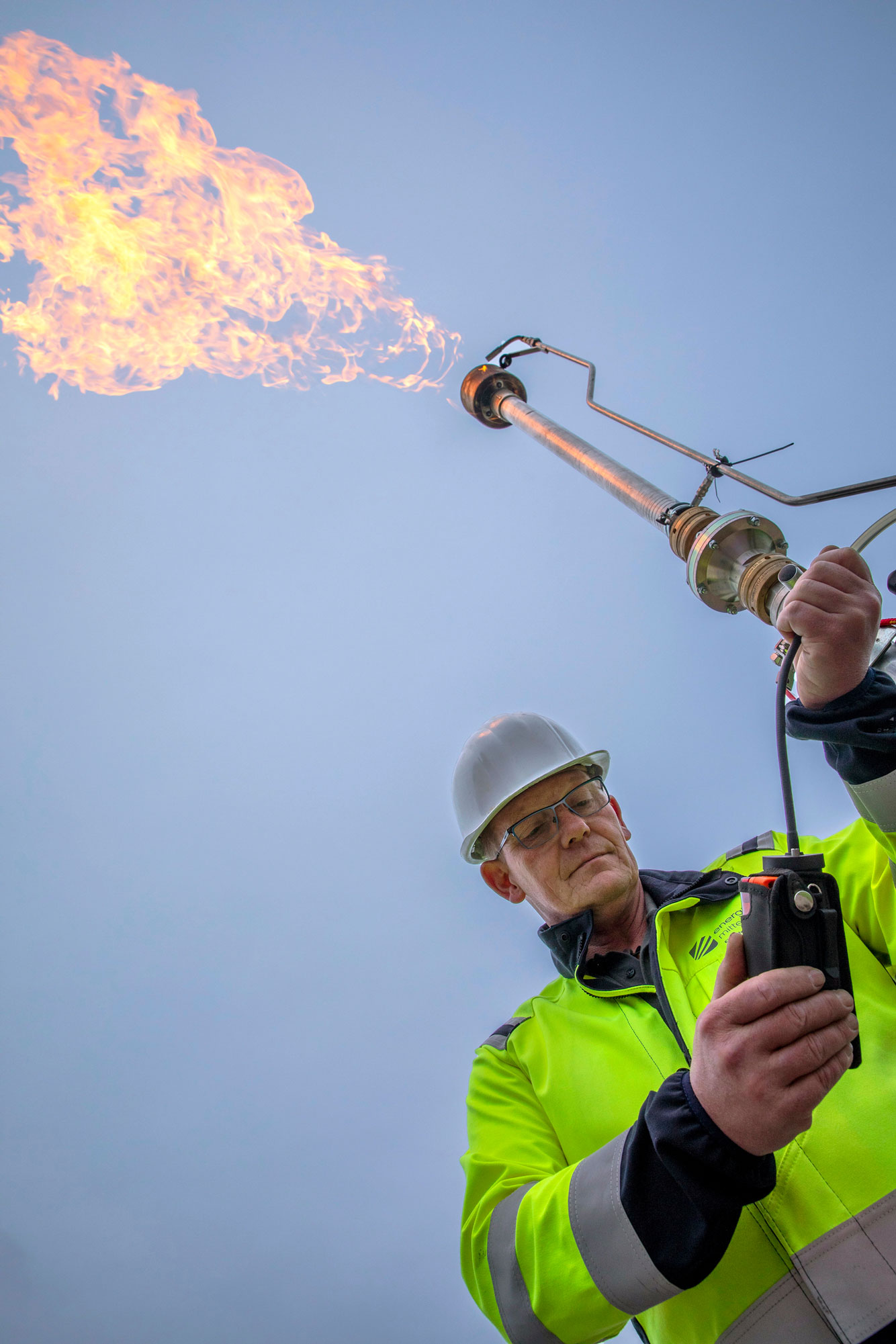 Ein Mann mit Schutzkleidung und Helm arbeitet an einer Erdgasfackel