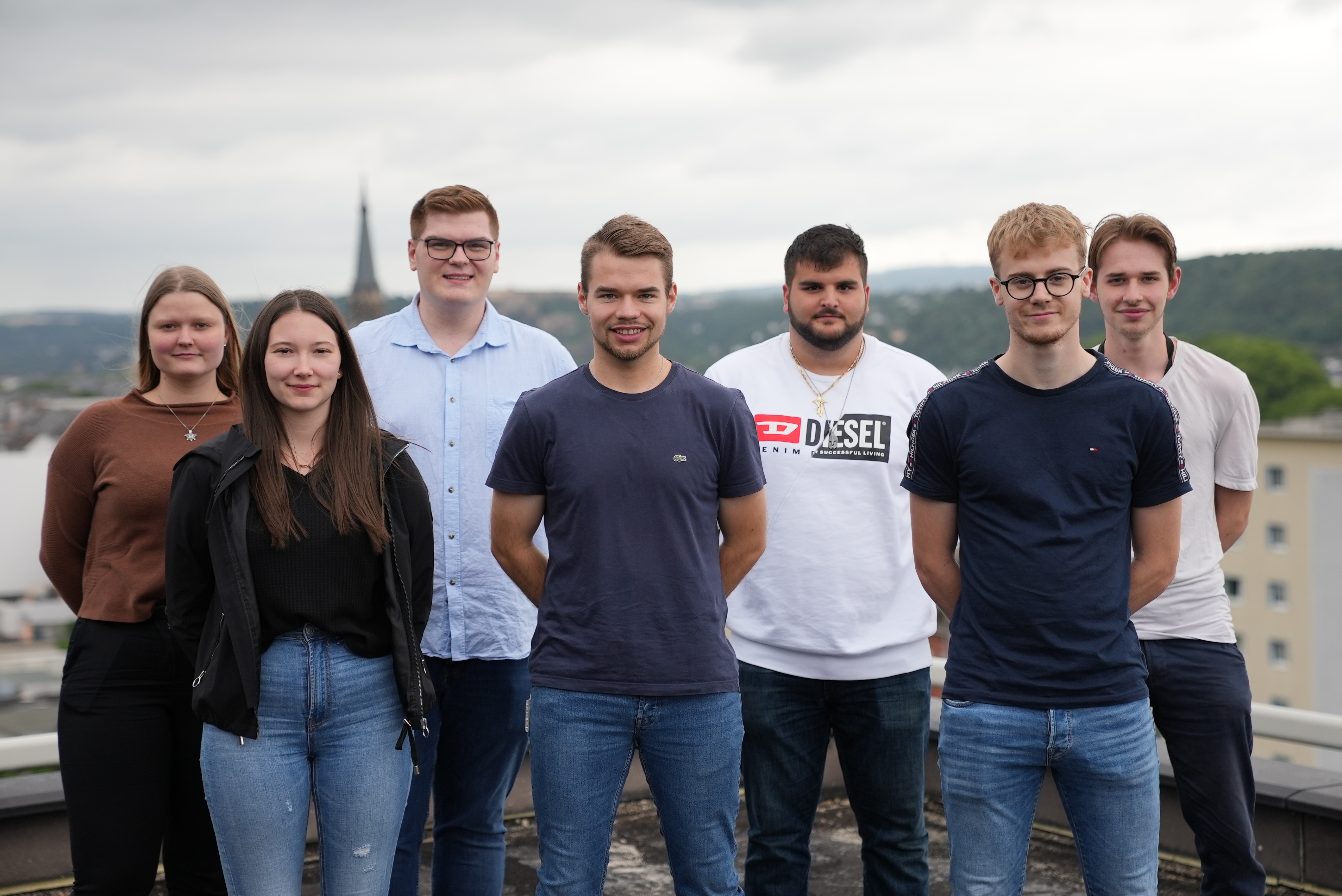Fünf junge Männer und zwei junge Frauen stehen auf einem Dach