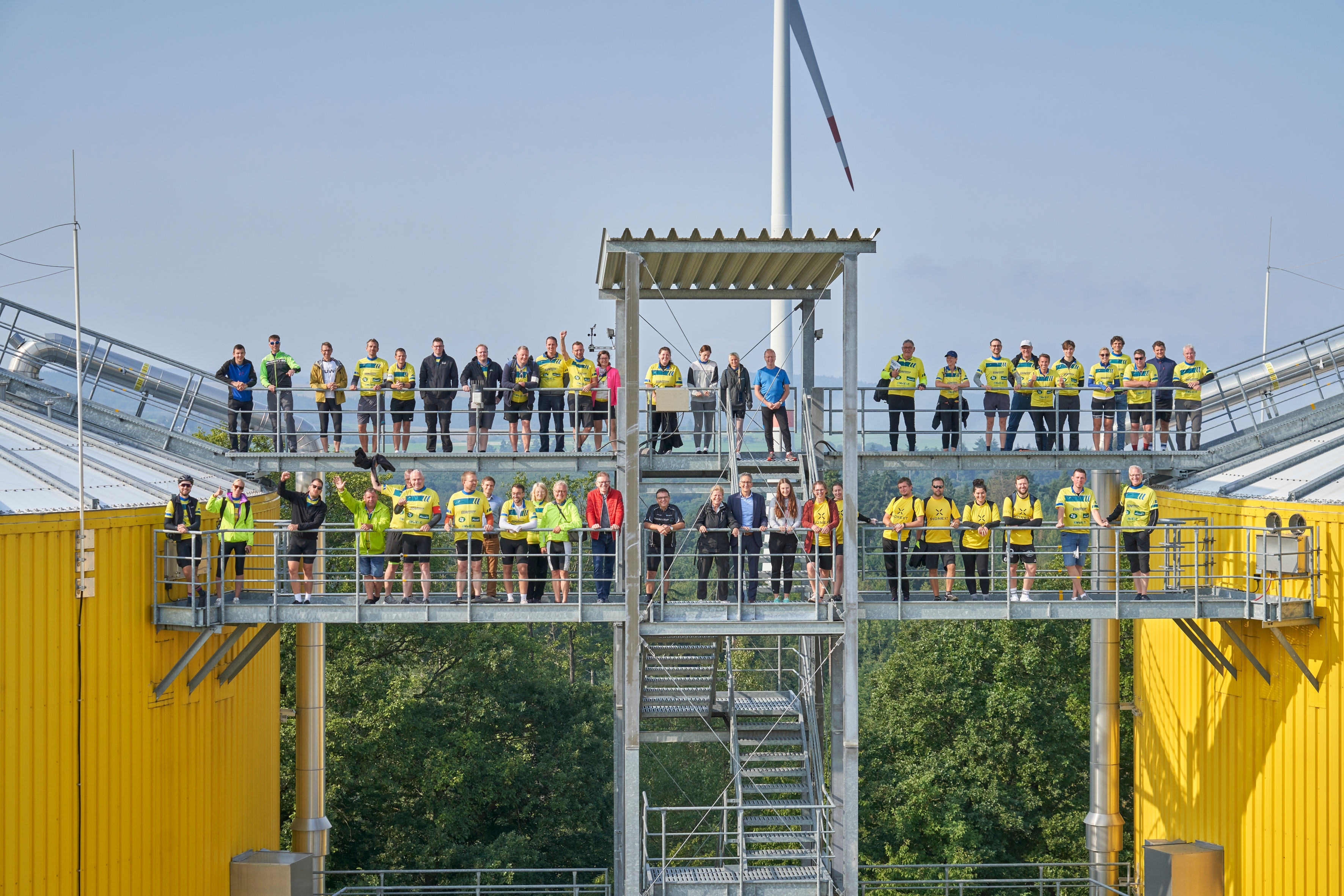Mehrere Menschen in Radkleidung stehen auf einem Übergang von einer Biogasanlage.