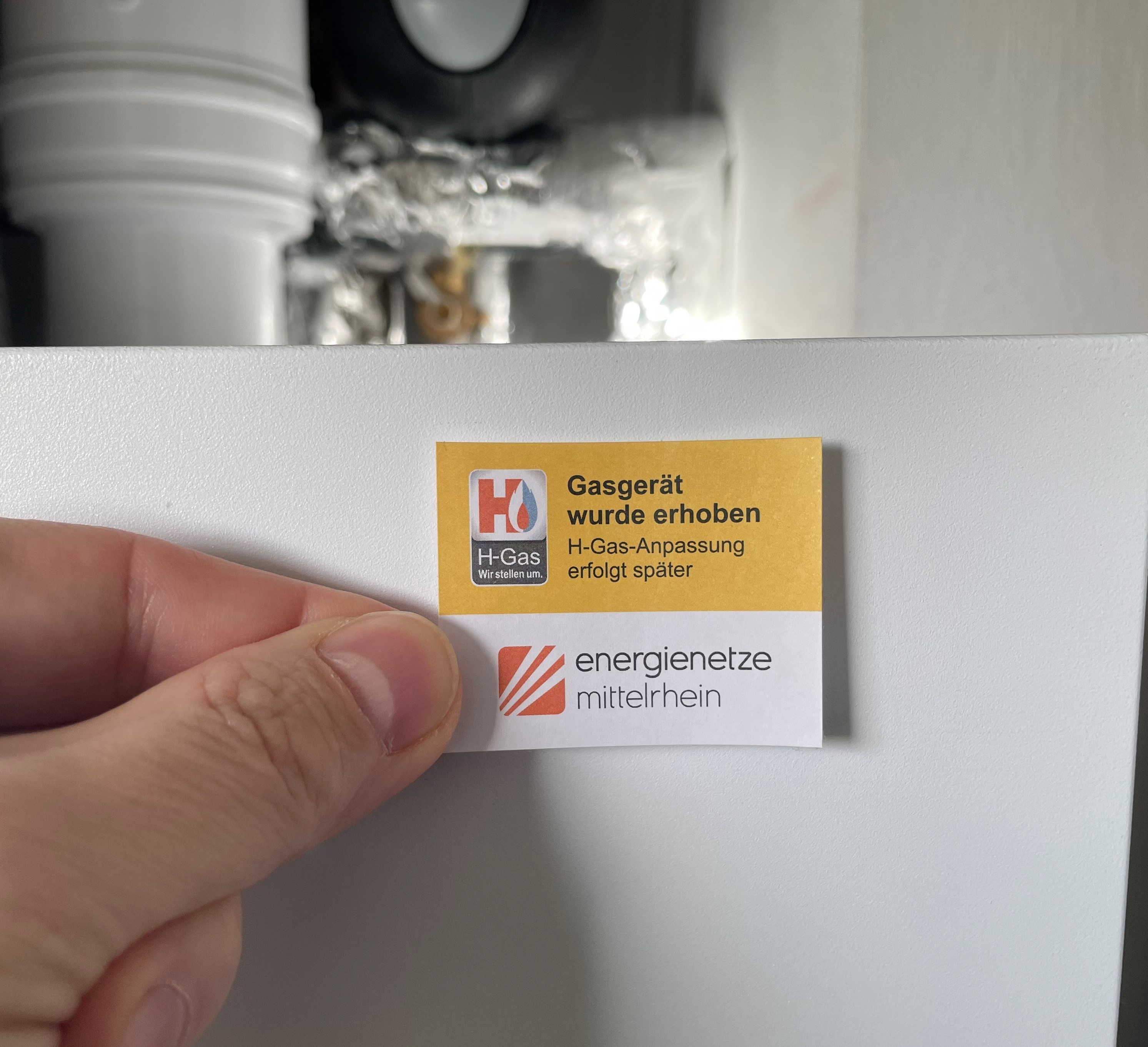 Eine Person hält einen Zettel mit der Aufschrift "Gasgerät wurde erhoben".