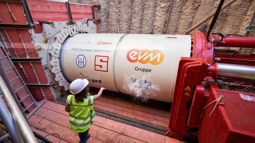 Eine Frau in Schutzkleidung tauft den Bohrkopf einer Trinkwasserleitung.