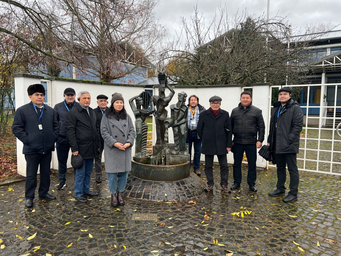 IMG_1917 Neun Menschen stehen vor einem Brunnen und lächeln freundlich