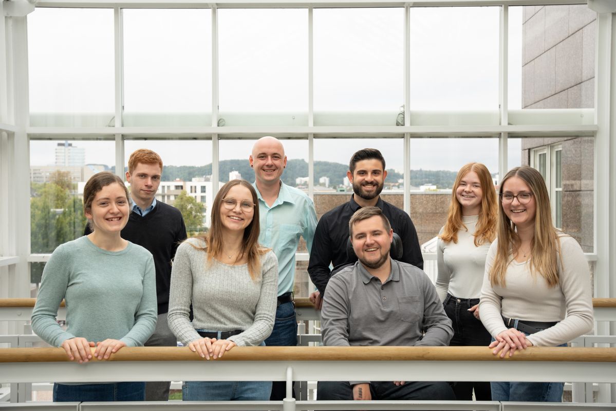 Vier junge Frauen und vier junge Männer lächeln freundlich
