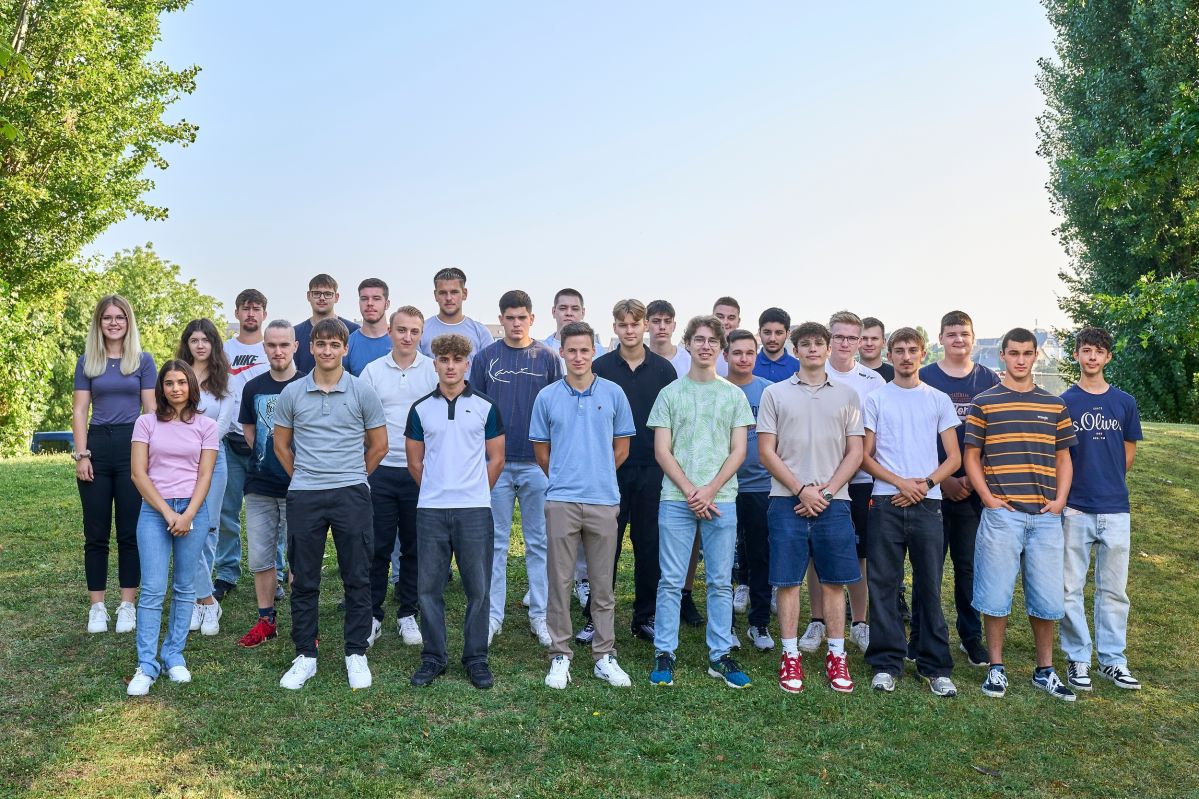 240902SDI1091 Mehrere junge Menschen stehen auf einer Wiese und lächeln freundlich