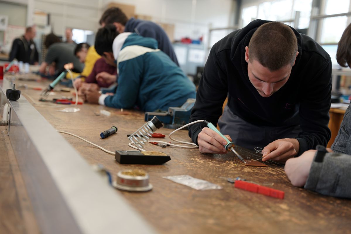 Ein junger Mann schweißt etwas zusammen in einer Werkstatt