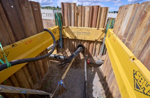 Reparatur Schaden: Gastransportleitung Andernach – Mayen / Straße: B 256 / Bereich Obere Löhr Straße Ein offenes Rohr mit Kabeln auf einer Baustelle. Das Rohr ist freigelegt und gelbe Holzbalken bilden eine Konstruktion um das Rohr.