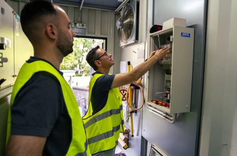 David Langner und ein Mitarbeiter der Energienetze Mittelrhein stehen in einem Technikraum vor einem geöffneten Schaltschrank. Beide tragen Warnwesten und betrachten die installierte Steuerungs- und Messtechnik. Die Aufnahme entstand während eines Praxiseinsatzes im Rahmen des Praktikumstags bei der evm-Gruppe.