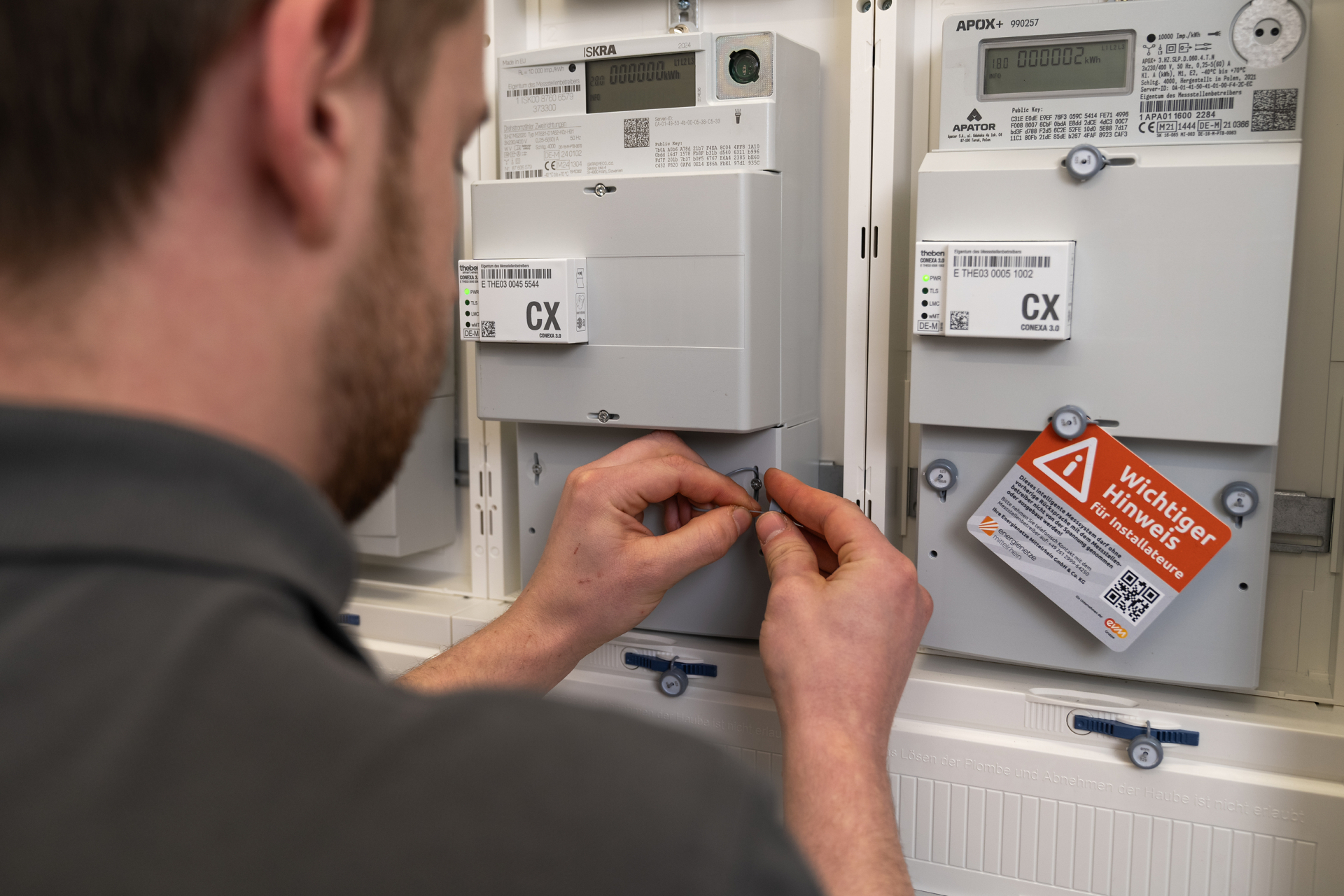 Eine Person installiert ein intelligentes Messsystem (Smart Meter) in einem Zählerschrank. Auf dem Bild sind digitale Stromzähler und die zugehörige Kommunikationstechnik zu sehen. Smart Meter ermöglichen die digitale Erfassung von Verbrauchsdaten und bilden eine wichtige Grundlage für die Digitalisierung der Energiewende.