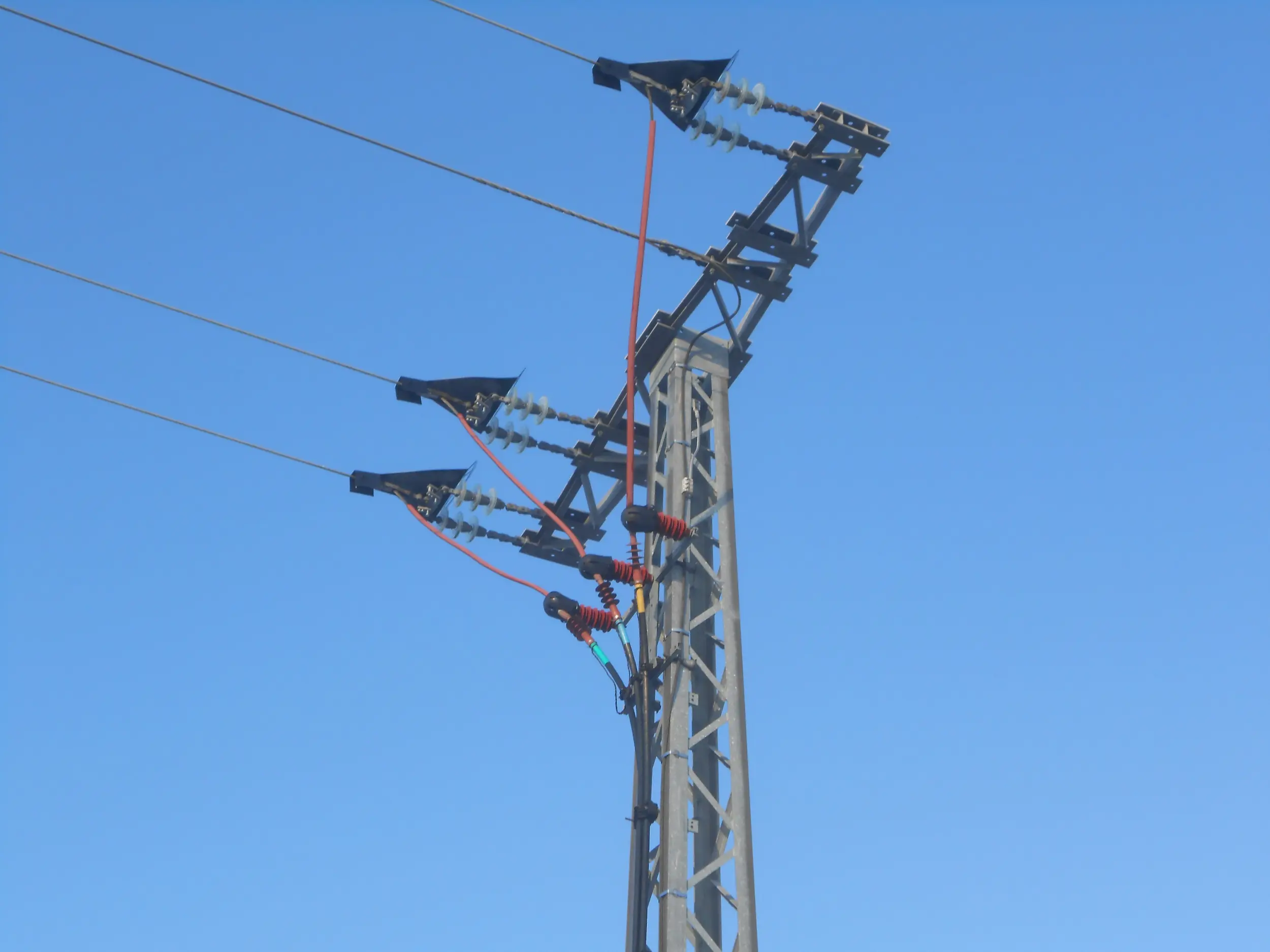 Strommast vor einem blauen Himmel.